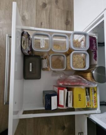 Netjes georganiseerde keukenla met overzichtelijk geordende etenswaren in een lichte en opgeruimde indeling.