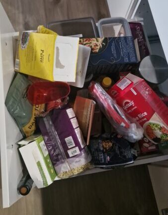 Overvolle keukenla met etenswaren en losse verpakkingen, symbool voor gebrek aan overzicht in de keuken.